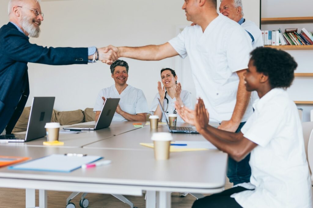 doctors compliment each other by shaking hands to the applause of their colleagues